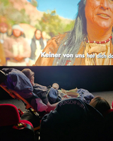 Jemand schaut einen Film mit untertitelter Szene im Kino aus einer Liege.
