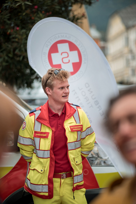 Ein junger Sanitäter in gelber Uniform steht vor einem Rettungswagen.