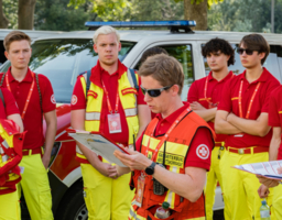 Gruppe von Menschen in Uniform stehen, in der Mitte steht die Einsatzleiterin mit einem Zettel in der Hand