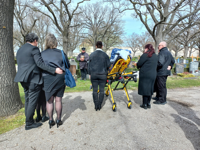 Trauergemeinde versammelt sich auf einem Friedhof um einen Sarg.
