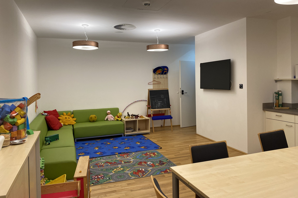 Begegnungsraum in der Ambulanten Familienberatung mit Esstisch, Couch, Spielsachen, Fernseher, Küche und Esstisch