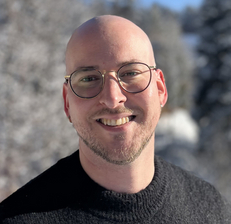 Ein lächelnder Mann mit Glatze steht in einer schneebedeckten Landschaft.