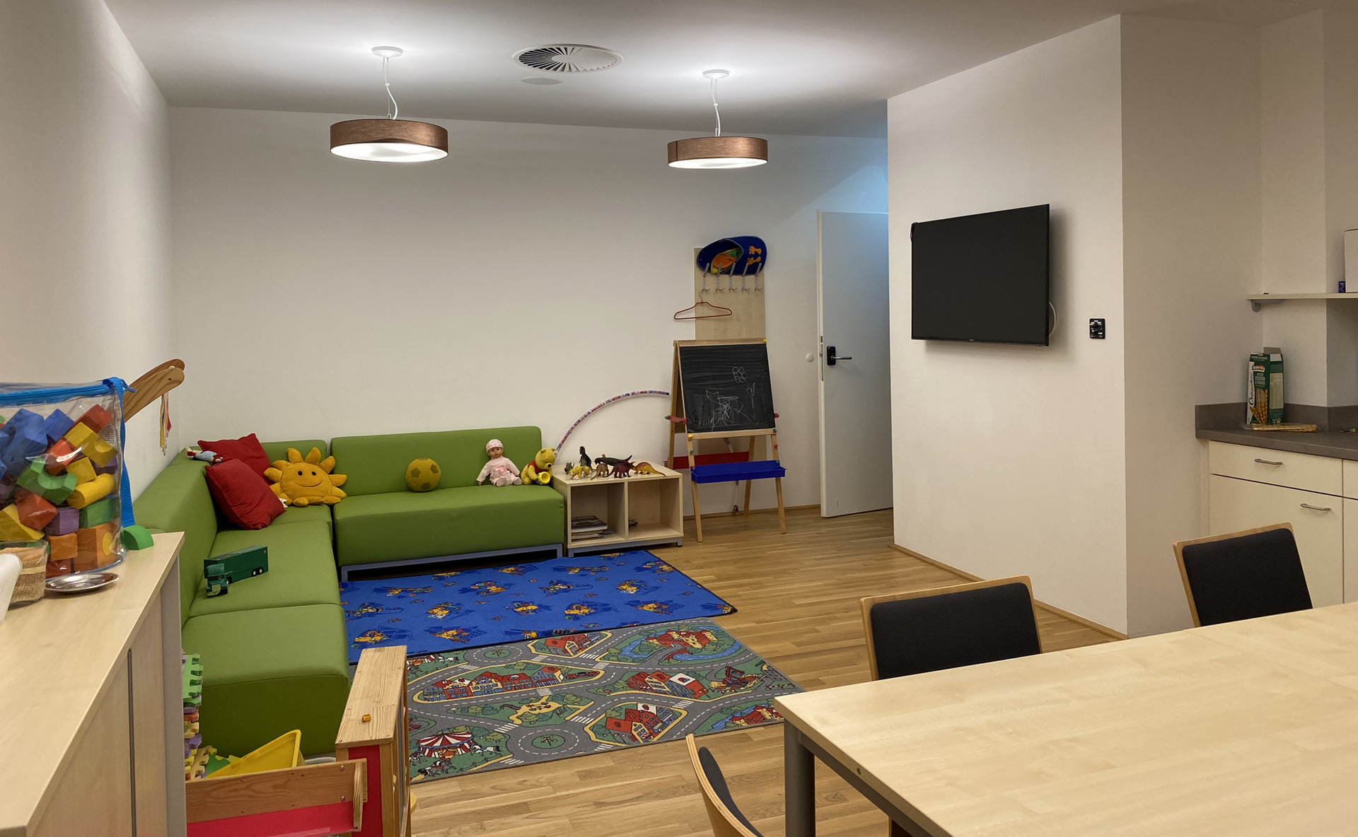 Begegnungsraum in der Ambulanten Familienberatung mit Esstisch, Couch, Spielsachen, Fernseher, Küche und Esstisch