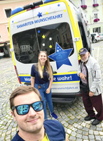 Selbstporträt mit zwei Personen vor einem Fahrzeug der Samariter-Wunschfahrt.